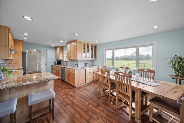 kitchen featuring light stone counters, dark wood-style flooring, glass insert cabinets, appliances with stainless steel finishes, and backsplash