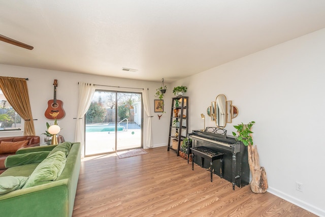 living area featuring light wood-style flooring, visible vents, and baseboards