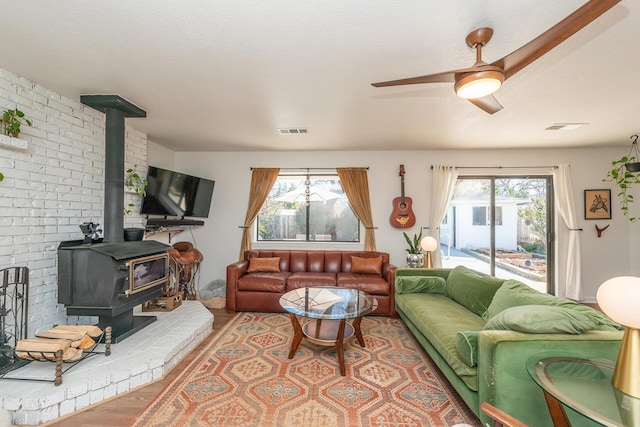 living area featuring visible vents, a wealth of natural light, wood finished floors, and a wood stove