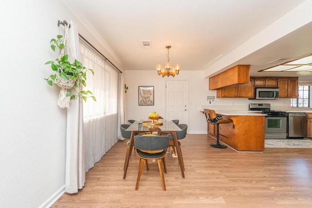 dining space with visible vents, a notable chandelier, light wood-style flooring, and baseboards