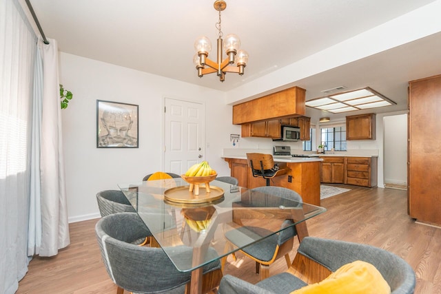 dining area featuring baseboards, light wood finished floors, visible vents, and an inviting chandelier