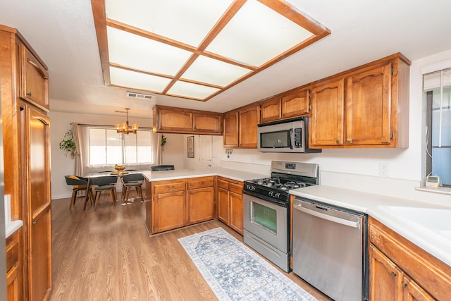 kitchen with visible vents, brown cabinetry, stainless steel appliances, light countertops, and light wood-style floors