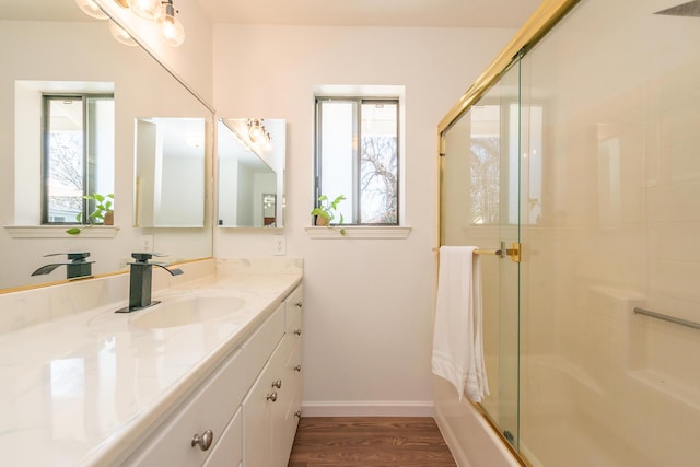 bathroom featuring shower / bath combination with glass door, vanity, baseboards, and wood finished floors