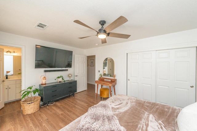 bedroom with arched walkways, a closet, visible vents, connected bathroom, and wood finished floors