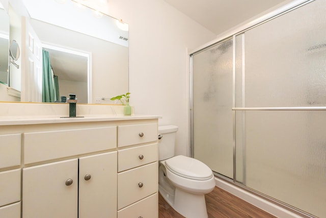 full bathroom with visible vents, toilet, wood finished floors, vanity, and a shower stall