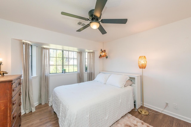 bedroom featuring a ceiling fan, wood finished floors, visible vents, and baseboards