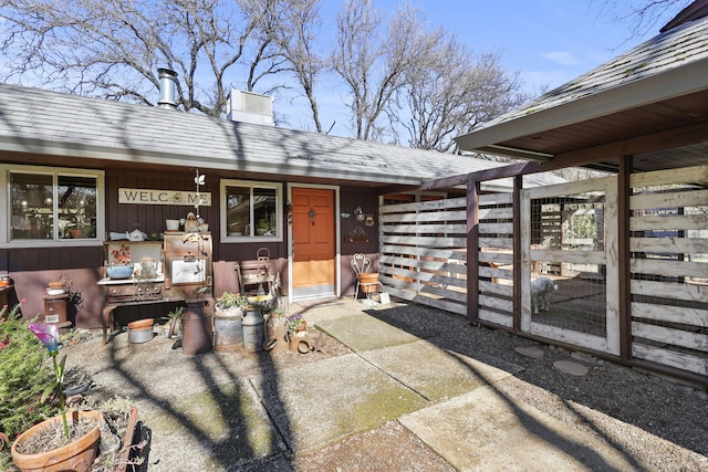 entrance to property with a patio area, a chimney, and roof with shingles