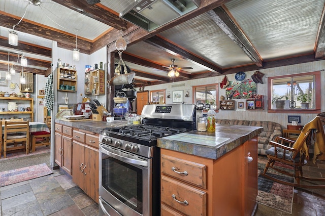 kitchen featuring dark countertops, gas range, stone tile flooring, and beamed ceiling