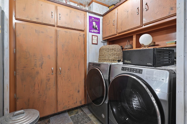 laundry room with stone tile floors, cabinet space, and washer and dryer