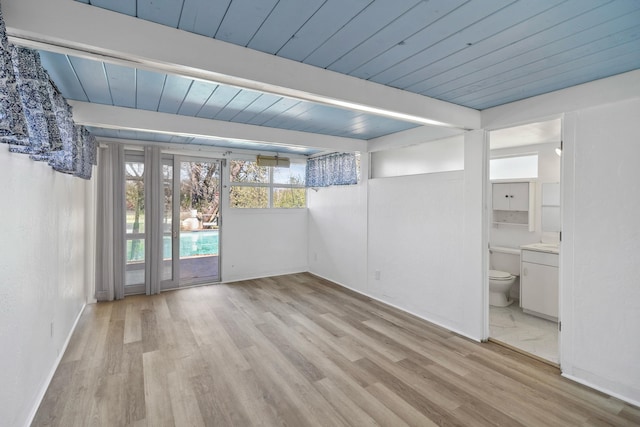 unfurnished room with light wood finished floors, wood ceiling, beam ceiling, and a wealth of natural light