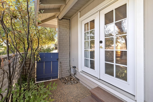 entrance to property featuring brick siding, fence, and french doors