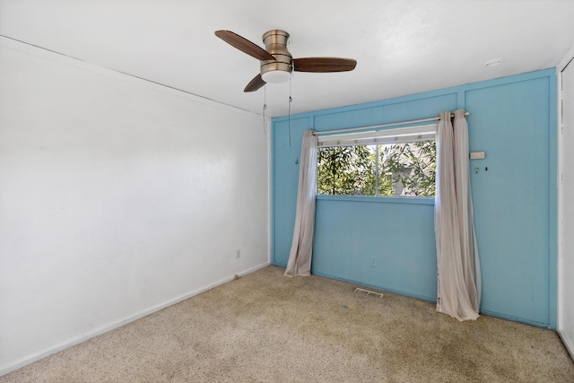 carpeted spare room with visible vents and a ceiling fan