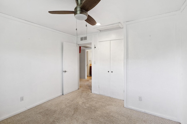 unfurnished bedroom with light colored carpet, visible vents, a ceiling fan, baseboards, and attic access