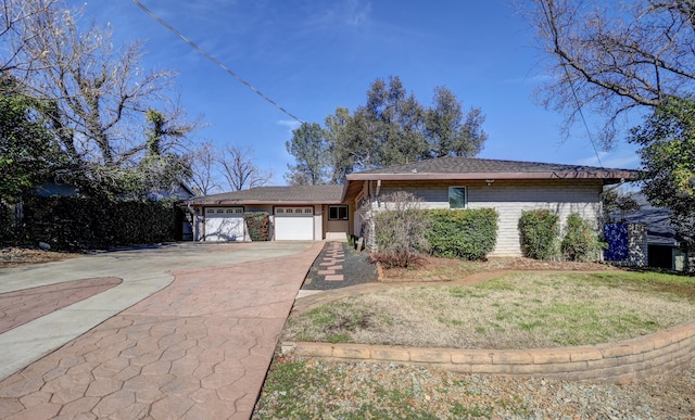 single story home with driveway, brick siding, an attached garage, and a front yard