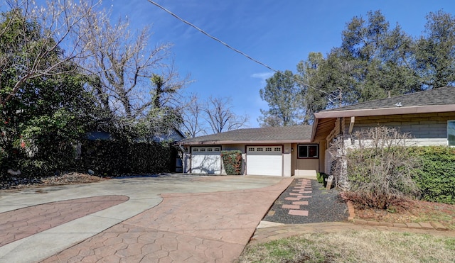 view of front of home featuring a garage, concrete driveway, and a shingled roof