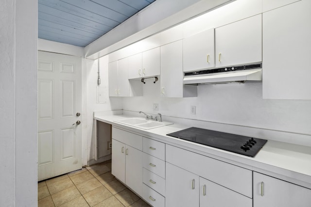 kitchen with light countertops, a sink, under cabinet range hood, and black electric stovetop