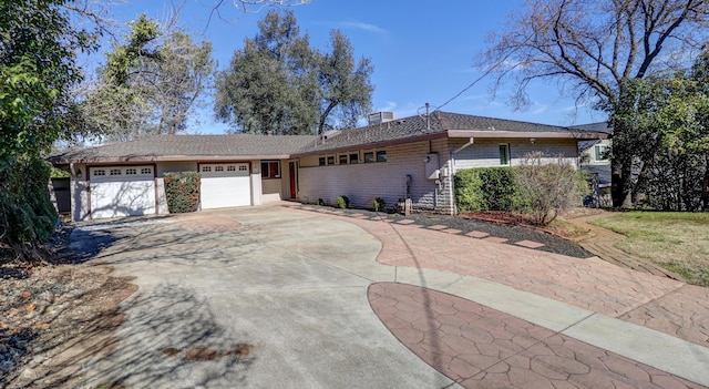 ranch-style home with a garage, concrete driveway, and a chimney