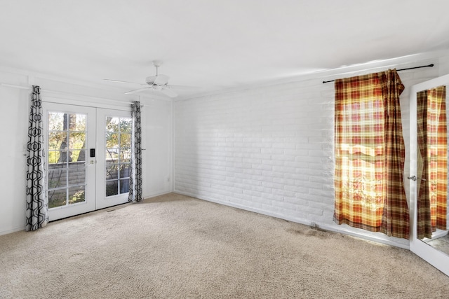 empty room featuring brick wall, french doors, carpet, and a ceiling fan