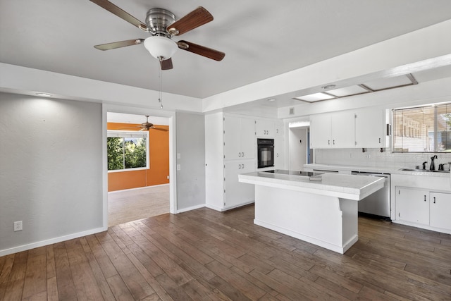 kitchen with tasteful backsplash, dark wood finished floors, black appliances, white cabinetry, and a sink