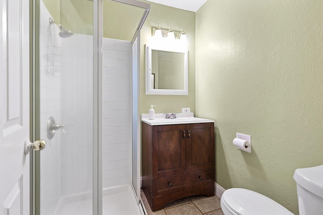 full bathroom with a shower stall, toilet, a textured wall, tile patterned floors, and vanity