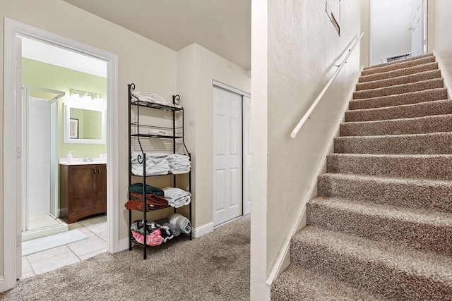 stairway with tile patterned floors, carpet, and baseboards