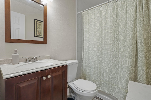 full bathroom with curtained shower, toilet, vanity, and a textured wall