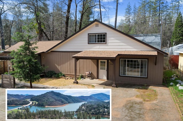 view of front facade featuring a patio, a water and mountain view, and roof with shingles