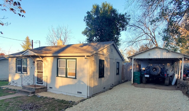 view of front of house featuring gravel driveway, a chimney, a shingled roof, crawl space, and a carport