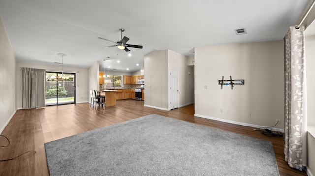 unfurnished living room featuring ceiling fan with notable chandelier, recessed lighting, wood finished floors, lofted ceiling, and baseboards