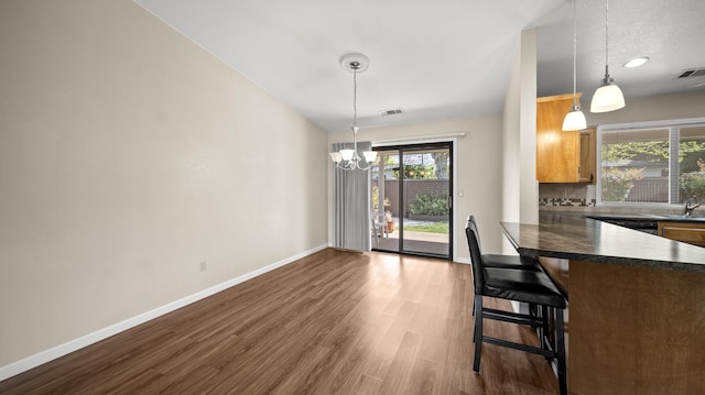 kitchen with baseboards, a notable chandelier, dark wood-style flooring, dark countertops, and backsplash
