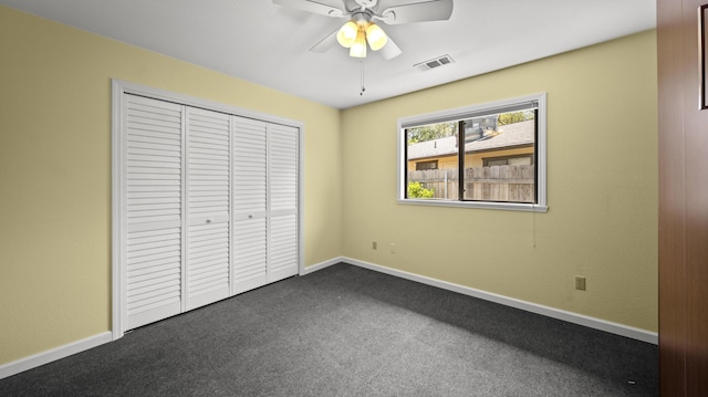 unfurnished bedroom featuring dark carpet, visible vents, baseboards, and a closet