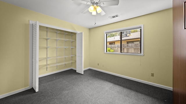 unfurnished bedroom featuring visible vents, baseboards, a ceiling fan, and dark colored carpet