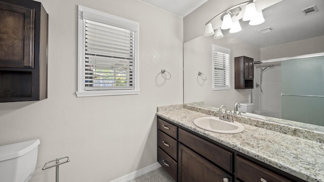 bathroom featuring visible vents, toilet, vanity, and a shower with door