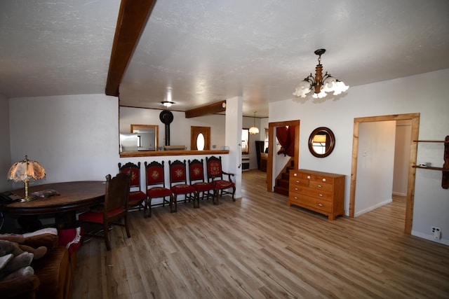 dining space featuring baseboards, wood finished floors, stairs, a textured ceiling, and a notable chandelier