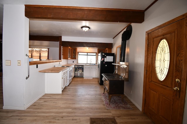 kitchen with baseboards, white cabinets, appliances with stainless steel finishes, light wood finished floors, and beamed ceiling