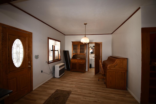 entryway with ornamental molding, light wood finished floors, baseboards, and heating unit