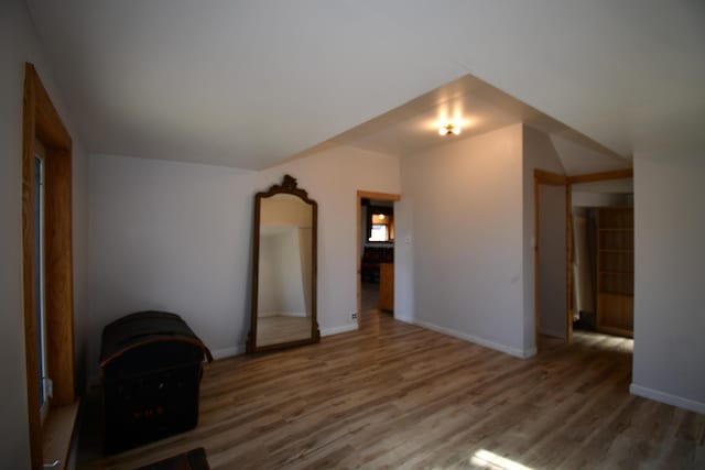 interior space featuring vaulted ceiling, wood finished floors, and baseboards