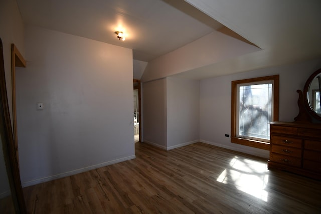 interior space featuring lofted ceiling, baseboards, and wood finished floors