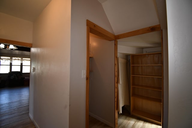 corridor with lofted ceiling, wood finished floors, and baseboards