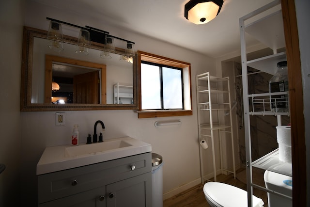 bathroom with toilet, baseboards, wood finished floors, and vanity