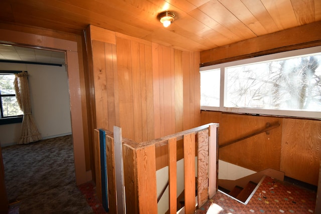 interior space featuring wooden ceiling, an upstairs landing, and wooden walls