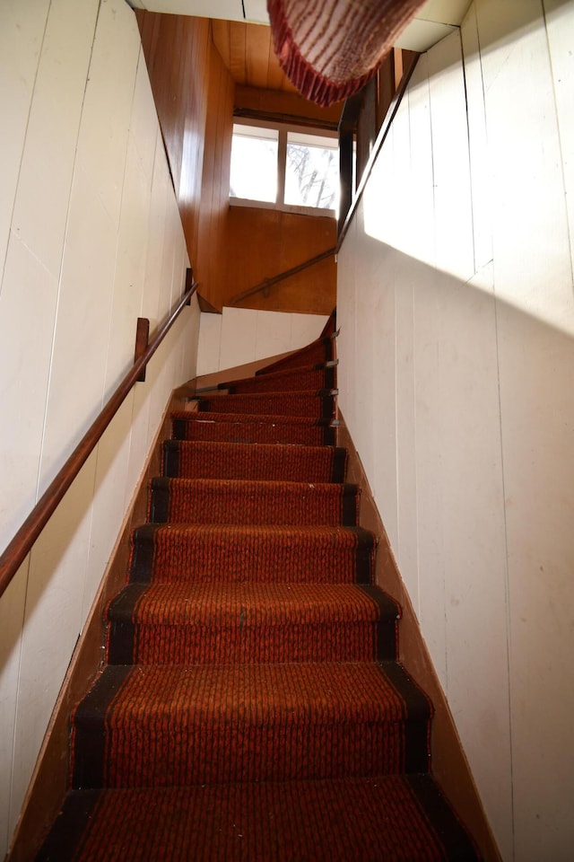 staircase with wood walls and a decorative wall