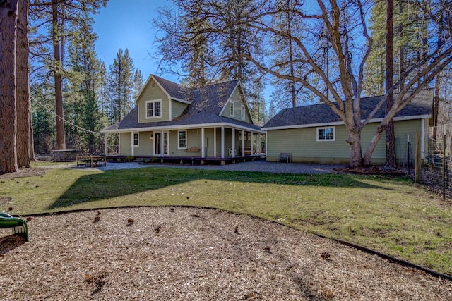 view of front facade with covered porch, roof with shingles, fence, and a front yard