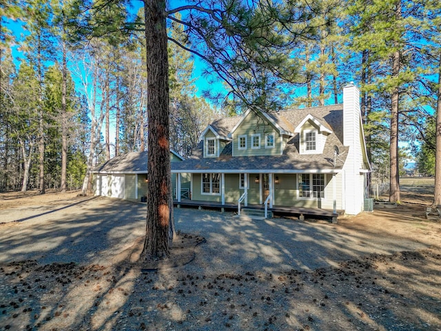 view of front of house featuring a porch, a chimney, and a garage