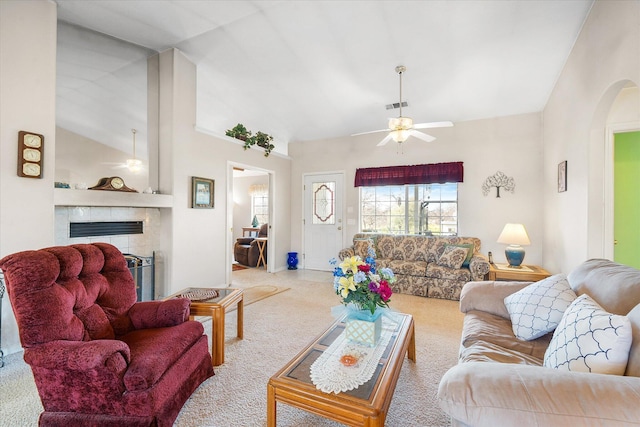 living room with a ceiling fan, a tile fireplace, visible vents, and arched walkways