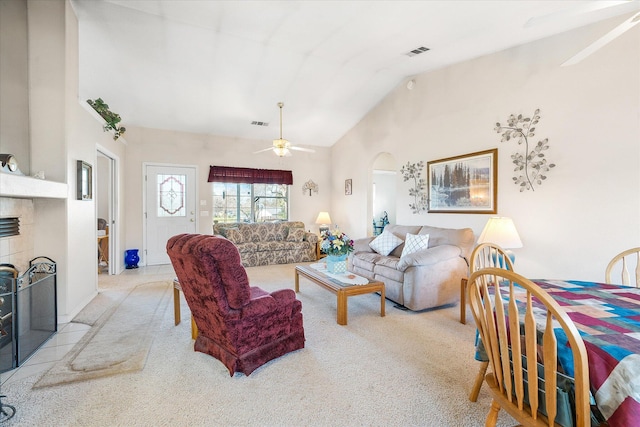 living area with light carpet, visible vents, arched walkways, a tile fireplace, and ceiling fan