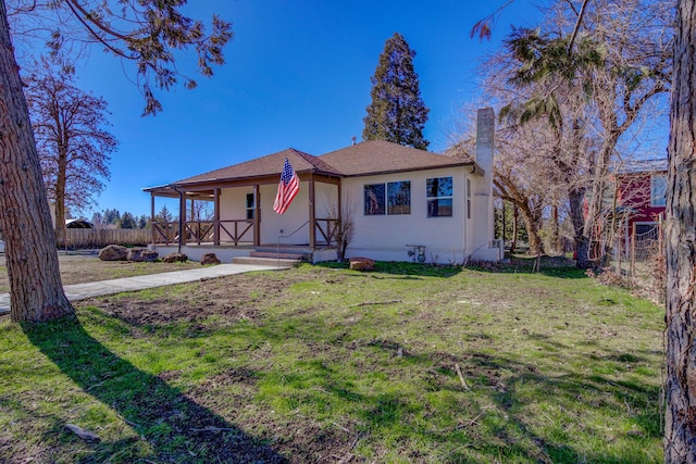 view of front of property with covered porch, fence, a front lawn, and stucco siding