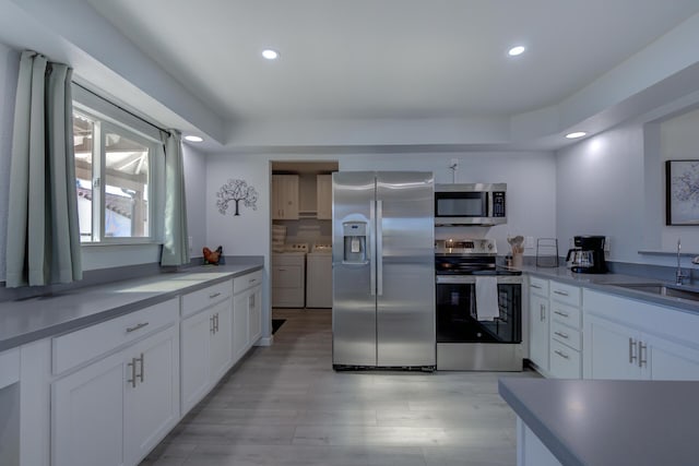 kitchen featuring recessed lighting, stainless steel appliances, separate washer and dryer, a sink, and white cabinets