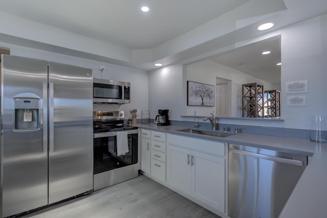 kitchen featuring recessed lighting, stainless steel appliances, a sink, white cabinetry, and light wood-type flooring