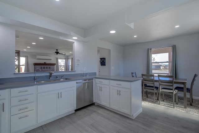 kitchen with a wall unit AC, recessed lighting, white cabinets, a sink, and dishwasher